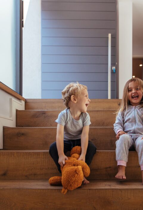 Lachende Kinder auf breiten Holzstufen zeigen, wie wichtig Sicherheit beim Treppen planen sind